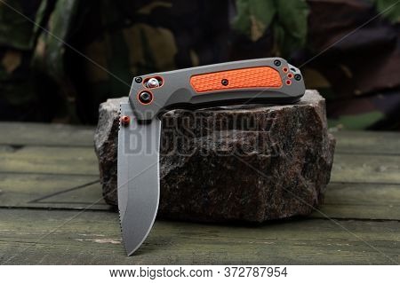 Very Sharp Knife With A Khaki And Orange Handle. The Knife Is In A Semi-folded Position.