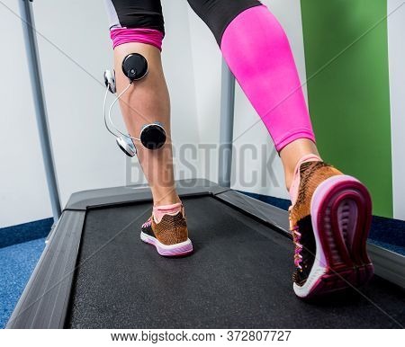 Young Sports Woman With Electrostimulator On The Muscles Of The Legs.