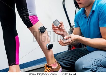 Physical Therapist Install Electrostimulator On The Muscles Of The Legs.