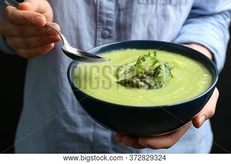 Woman Eating Delicious Asparagus Soup On Black Background, Closeup