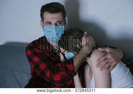 Couple In Medical Masks Watching Tv While Man Hugging Upset Girl