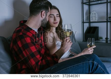 Girl With Closed Eyes Sitting On Sofa Near Boyfriend With Glasses Of White Wine