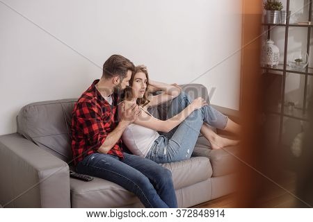 Focus Of Young Man Calming Upset Girl While Sitting On Sofa Together