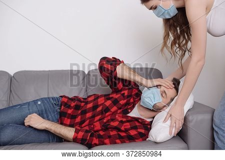 Woman Touching Pillow While Sick Boyfriend Lying On Sofa And Holding Hand On Head