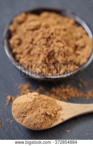 Guarana Powder In A Wooden Spoon And A Ceramic Cup On A Black Slate Background.brown Shredded Guaran