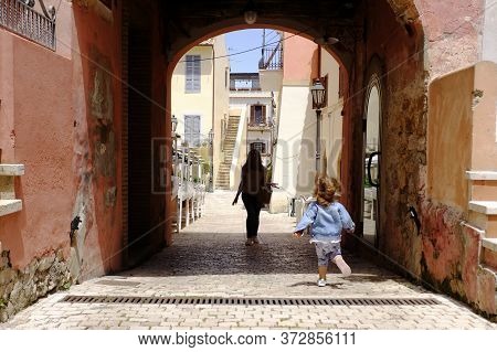 A Little Girl Run Towards Her Mom In The Picturesque Italian Village. San Felice Circeo, Lazio, Ital