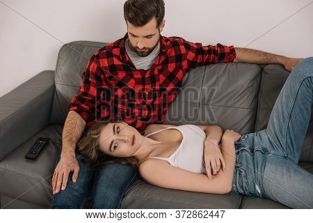 Angle View Of Depressed Young Couple On Sofa At Home During Quarantine