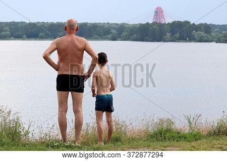 Beach Vacation And Summer Leisure, Old Man And Little Boy In Trunks Standing On Background Of Moscow