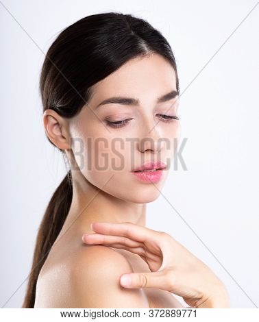 Portrait of beautiful young brunette woman with clean face. Beautiful face of young adult woman with clean fresh skin - isolated on white. Front portrait of woman with beauty face. Beauty concept 
