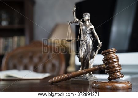 Law Theme. Judge Chamber. Gavel And Themis Statue On Brown Shining Desk. Collection Of Legal Books I