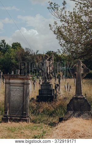 London, Uk - June 16, 2020: Angel Statue On A Tomb Amongst Tombstones Inside Hampstead Cemetery, A H