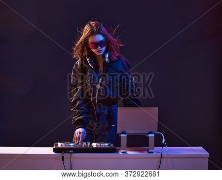 Stylish Dj Girl With Headphones And Glasses On The Bomber Jacket Mixes The Music At The Party And Ne