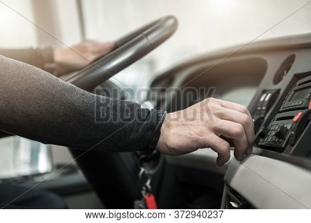 Public Transportation Concept. Caucasian Coach Bus Driver Keeping Steering Wheel And Changing Radio 
