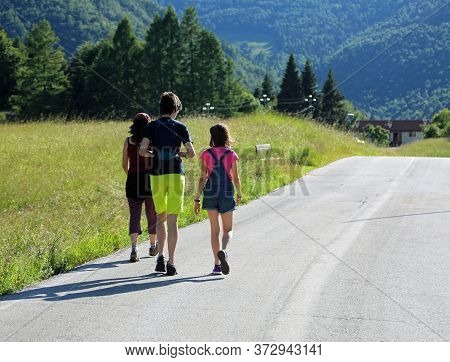 Family With Young Mother With Two Young Children While Walking In The Street In The Hills In Summer