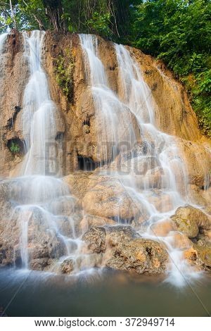 Waterfall Landscape View Of Fresh Water Flows Over A Vertical Drop To Green Field In Tropicana