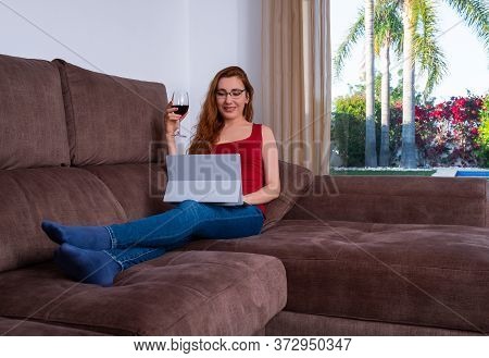 Woman Laying Comfortably And At Her Living Room On A Couch And Working.