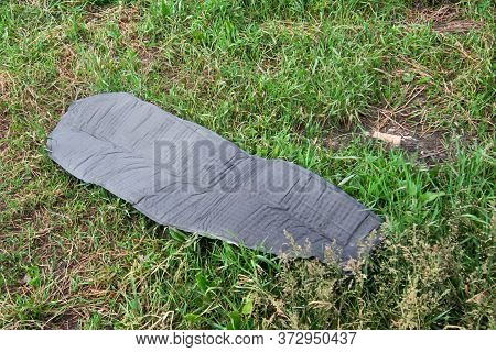 Straightened Self-inflating Green Tourist Mat Lies On Green Grass