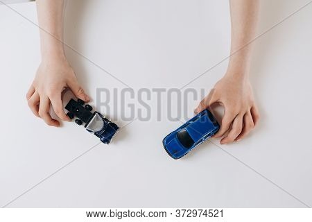 Two Toy Cars In Children's Hands On A White Background