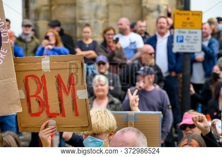 Richmond, North Yorkshire, Uk - June 14, 2020: Homemade Blm Sign With Out Of Focus Angry British Cou