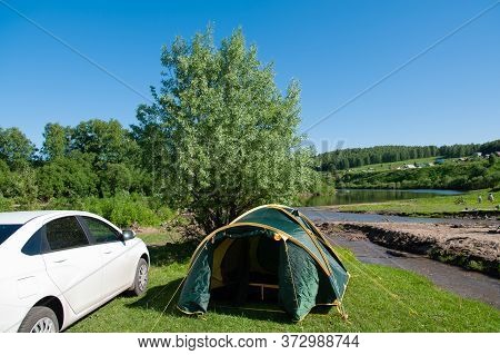 The Tent Stands On The Banks Of The River On A Sunny Day