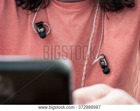 Man Wearing Intra Auricular Headphones Around His Neck. Headphones With Professional Balanced Cable.