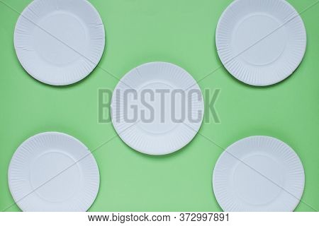 The Layout On A Green Background From Paper Disposable Plates. Caring For The Environment. Recycling