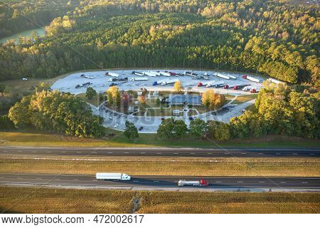 Top View Of Large Rest Area Near Busy Multilane American Freeway With Fast Moving Cars And Trucks. R