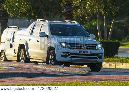 Side , Turkey -  January  29, 2023:      White  Volkswagen Amarok   Driving   On The Street On A War