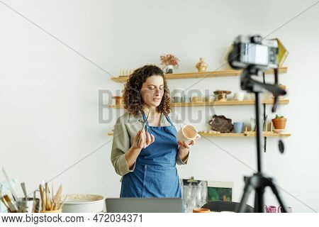 Females Potter Making A Vlog, Recording Online Course, Lessons In Her Studion With Earthenware Shelf