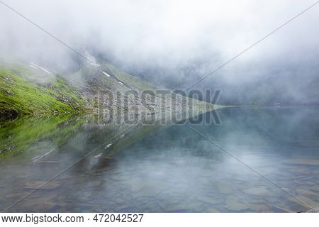 View Of Hemkund Sahib Glacier Lake Or Lake Of Snow With Fog And Reflection. The Lake Is A Must For S