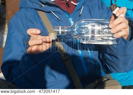 Unrecognizable Woman Hands Pooring Vodka In The Bottle Cap. Finland Vodka. Picture Taking Outdoors, 