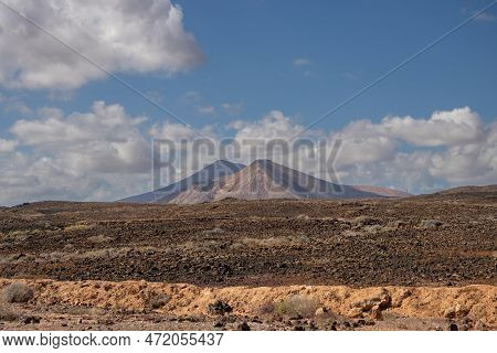 Stone Volcanic Desert And Mountains On A Horizon. Durch Park (parque Holandes). Blue Sky With White 