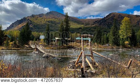 Rope Bridge In The Mountains Connecting The Two Banks Of A Small Mountain River.