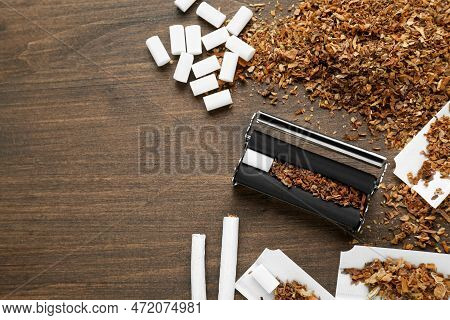 Flat Lay Composition With Roller And Tobacco On Wooden Table, Space For Text. Making Hand Rolled Cig