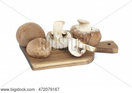 Fresh Baby Bella Or Cremini Whole Mushrooms On Wooden Cutting Board Isolated On White Background