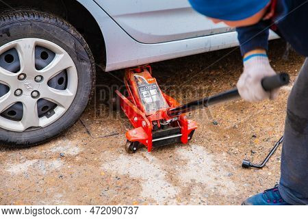 Male Man Jacked Up Blue Hyundai Car With Red Jack Outside. Astana, Kazakhstan - 10.24.2022