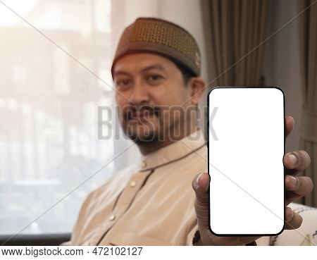 Close Up Of Young Asian Muslim Man's Hand Holding Mobile Phone With Smiling Expression On Face. Isol