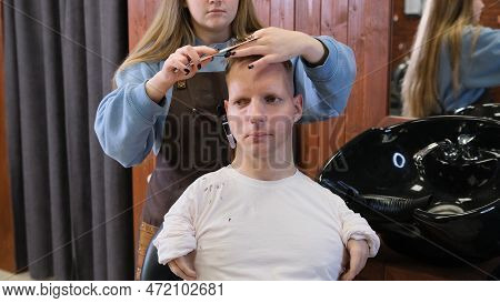 A Hairdresser Girl In A Beauty Salon Does A Haircut And Hair Styling For A Man With Disabilities.