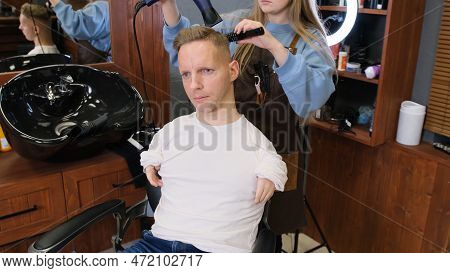 A Hairdresser Girl In A Beauty Salon Does Hair Styling For A Man With Disabilities.