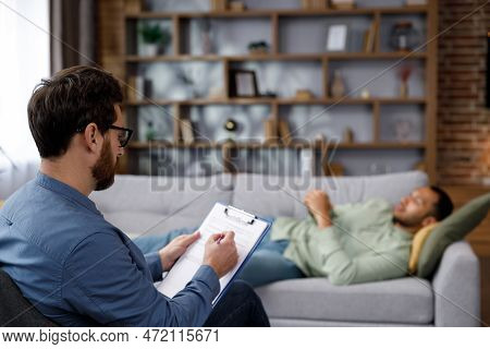 A Visit To The Psychologist Of An African American Man. A Handsome Man Is Lying On The Couch And Tal