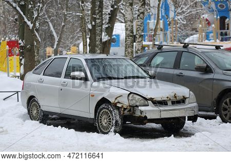 An Old Gray Rusty Wrecked Car Is Parked In The Yard In The Snow, Podvoysky Street, St. Petersburg, R