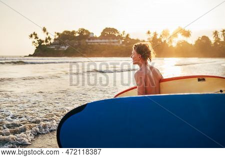 Portrait Of A Handsome Teen Boy Surfing Rashguard On The Sand Indian Ocean Beach With Sunset On Back