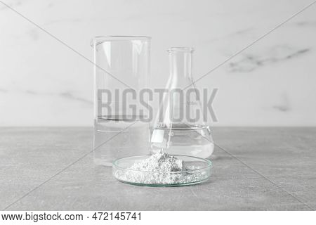 Petri Dish With Calcium Carbonate Powder And Laboratory Glassware On Light Grey Table