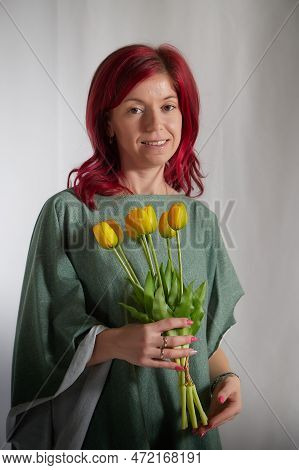 Beautiful Woman With Red Hair In Yellow Dress On A Light Background Holds Tulips. Inernational Woman