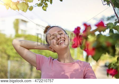 Portrait Of Happy Beautiful Girl, Young Positive Woman Is Smelling Beautiful Yellow Flowers In The G