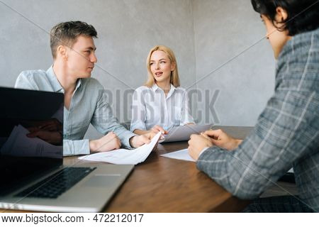 Low-angle View Of Serious Hr Managers Advisors Interviewing Young Male In Office. Employers Holding 