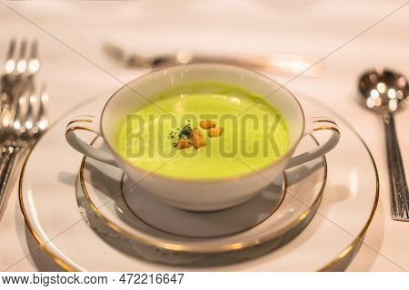 Green Peas Creamy Soup In A White Bowl Decorated With Gildings As Appetizer Of A Restaurant Of Frenc