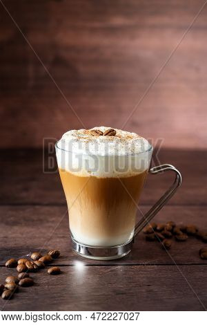 Glass Cup Of Layered Coffee Drink With Milk Foam, Coffee Beans, Wooden Background And Copy Space