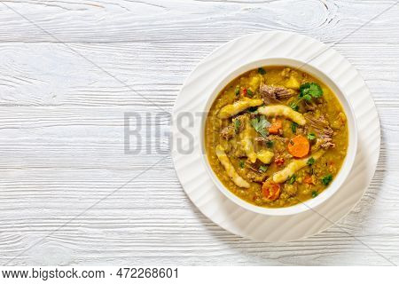 Gungo Peas, Pigeon Peas Soup With Dumplings , Vegetables And Beef In White Bowl On White Wood Table,
