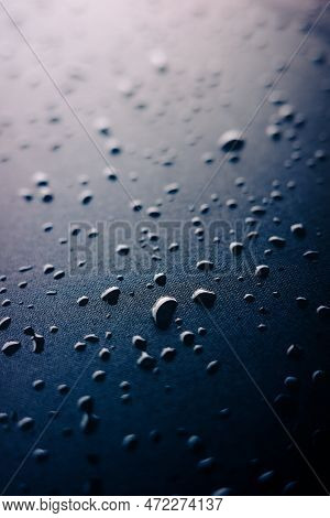 Selective Focus On Water Drops On Slippy Surface Of Black Synthetic Fabric With Bright Light From Ba